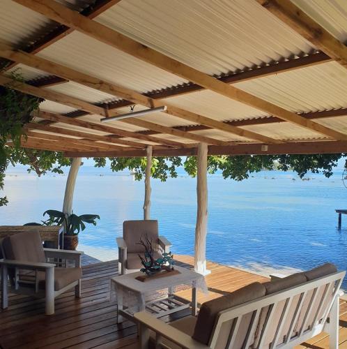 eine Holzterrasse mit Stühlen und einer Pergola mit Blick auf das Wasser in der Unterkunft Fare Tetahora in Tevaitoa