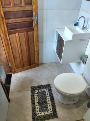 a bathroom with a toilet and a sink and a rug at Casa do Campo in Ilha do Mel