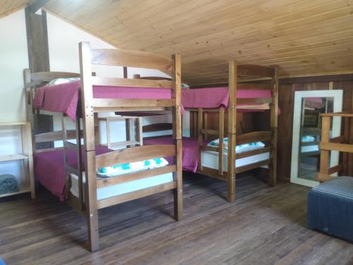 a room with three bunk beds in a cabin at Casa do Campo in Ilha do Mel