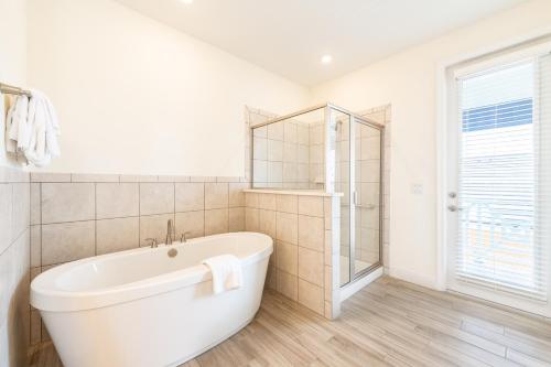 a white bathroom with a tub and a shower at Margaritaville Cottages Orlando with H2O Waterpark by Rentyl in Kissimmee