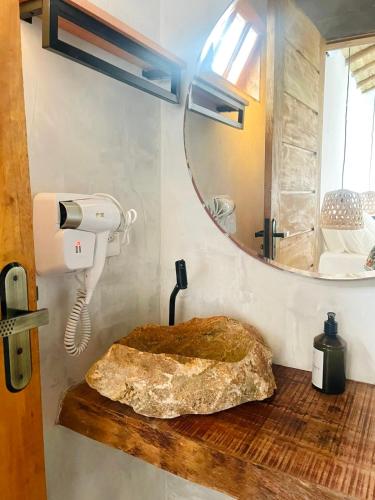 a bathroom with a mirror and a rock on a wooden counter at Villa Joá - Suites in Trancoso