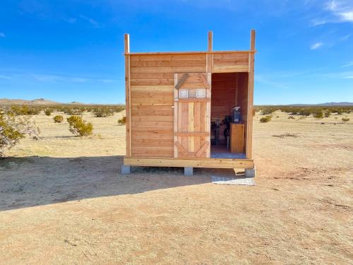 a wooden out house in the middle of the desert at Beysicair Tents & Campground in California City