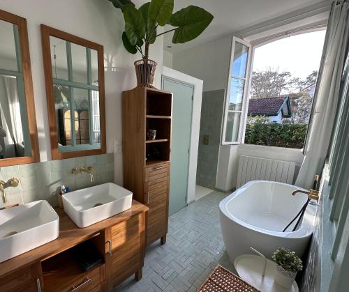 een badkamer met 2 wastafels, een bad en een plant bij Magnifique Villa 500m Océan et 5 min Lac Hossegor in Capbreton