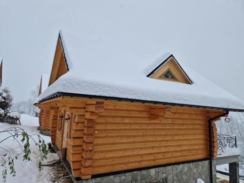 a log cabin with snow on top of it at Domki po balu 