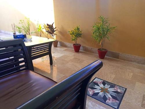 卡拉奇的住宿－Furnish Rooms Near Jinnah Airport，客厅配有长凳、桌子和盆栽植物