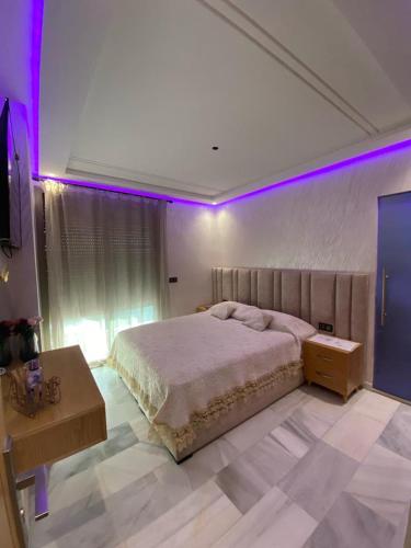 um quarto com uma cama grande e luzes roxas em Appartement neuf et élégant em Fez