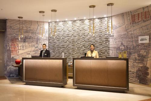 two men are standing behind two desks in a lobby at Le Méridien Santiago in Santiago