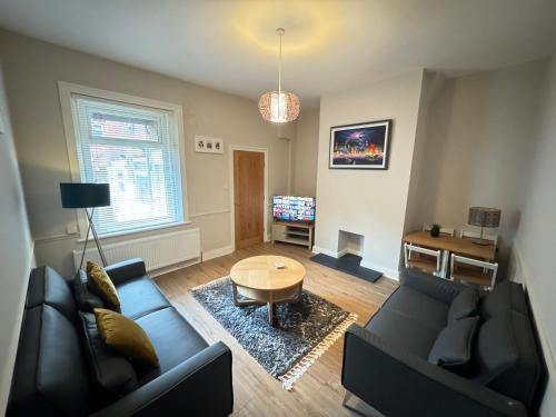 ein Wohnzimmer mit einem Sofa und einem Tisch in der Unterkunft Rockcliffe Retreat, Stylish Coastal Apartment in Whitley Bay