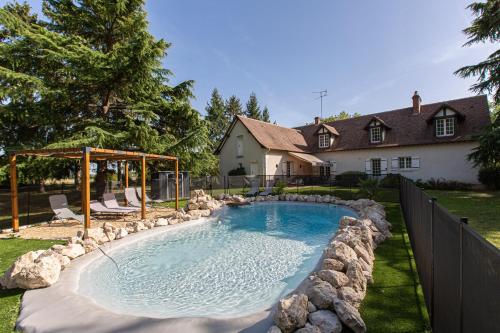 - une piscine entourée de rochers dans une cour dans l'établissement Le Domaine de Baracas 4 étoiles - Le Grand et le Petit Gîte - piscine-SPA-billard-baby-foot-cheminée - 18 personnes, à Huisseau-sur-Mauves