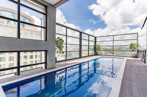 una piscina en un edificio con ventanas en Flat duplex com serviço de camareira e enxoval completo - ao lado do parque Ibirapuera, en São Paulo
