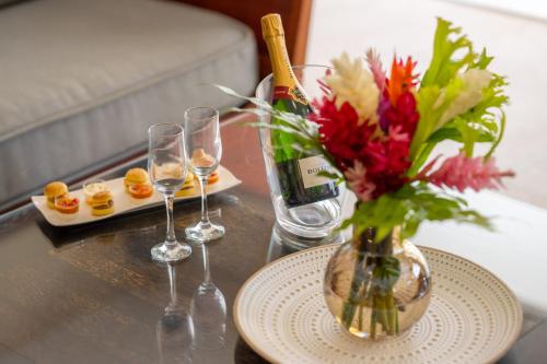 a table with a vase of flowers and wine glasses at Physacap Suites & Villas in Le François