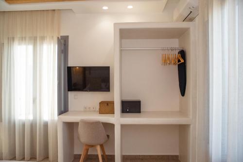 a room with a white desk with a chair and a tv at Anais Of Naxos in Agia Anna Naxos