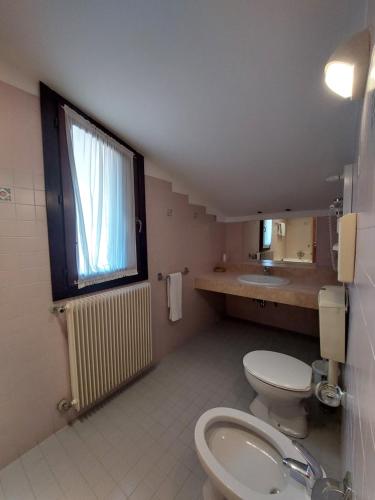 a bathroom with a toilet and a sink and a window at Albergo Alla Pineta in Montebelluna