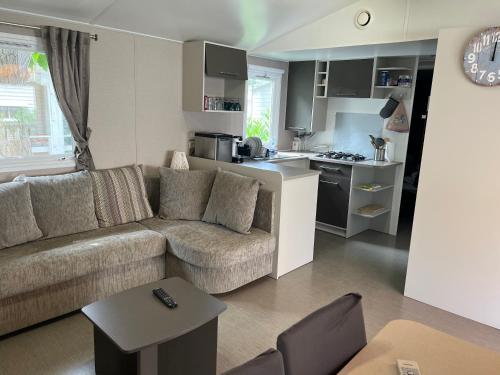 sala de estar con sofá y cocina en Mobil home camping 4* la carabasse Vias en Vias