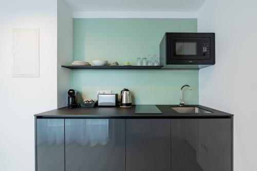 a kitchen with a counter with a microwave and a sink at Nena Apartments Berlin Adlershof in Berlin