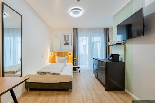 a bedroom with a bed and a desk and a tv at Nena Apartments Berlin Adlershof in Berlin
