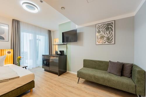 a bedroom with a bed and a couch and a tv at Nena Apartments Berlin Adlershof in Berlin
