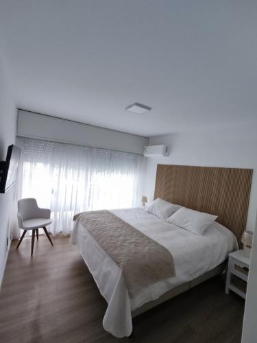 a bedroom with a large bed and a chair at Hermoso Apartamento de 3 dormitorios en punta del este in Punta del Este