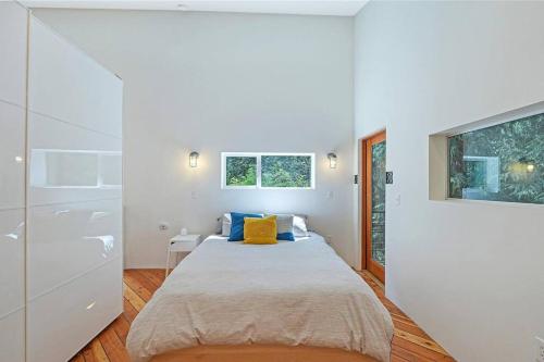 een witte slaapkamer met een bed en een televisie bij Guemes Island Road Modern Home in Anacortes