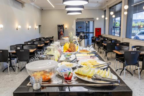 a long table with food on it in a room with chairs at Mirante Hotel in Governador Valadares