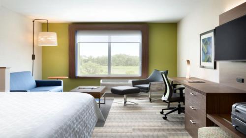 a hotel room with a bed and a desk and chairs at Holiday Inn Express - New Rochelle, an IHG Hotel in New Rochelle