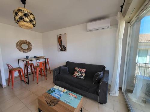 ein Wohnzimmer mit einem Sofa und einem Tisch in der Unterkunft Charmant T2 climatisé proche Calvi centre in Calvi