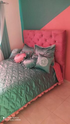 a bed with a pink headboard and pillows on it at Suisse.Ch in San Pedro de Macorís