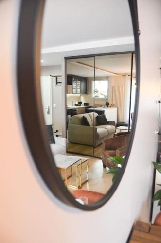 un miroir reflétant le salon avec un canapé dans l'établissement Le cocon 56, à Vincennes