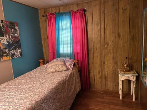 a bedroom with a bed and a window with pink curtains at Air b/b lodge in Windsor