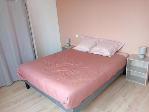 a bedroom with a bed with pink sheets and pillows at Gîtes Ti Tud-Kozh Le Guébriand et L'Arguenon in Pluduno
