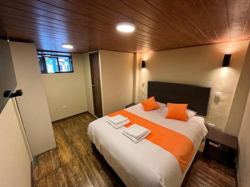 a bedroom with a large bed with orange pillows at Casa Virgen del Carmen in Cusco