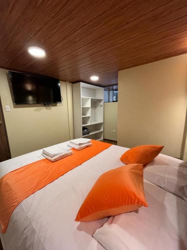 a large bed with orange pillows in a bedroom at Casa Virgen del Carmen in Cusco