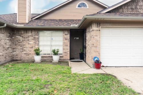 a house with two white garage doors and two potted plants at Cozy 3BR Home Escape, Modern & Serene in Dickinson