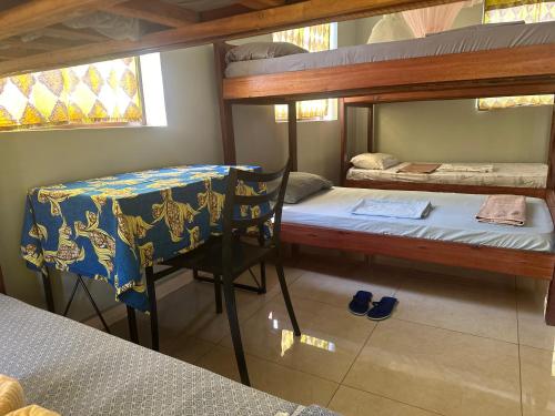 um quarto com 2 beliches, uma mesa e uma cadeira. em Missions Cafe Arua - GuestHouse em Arua