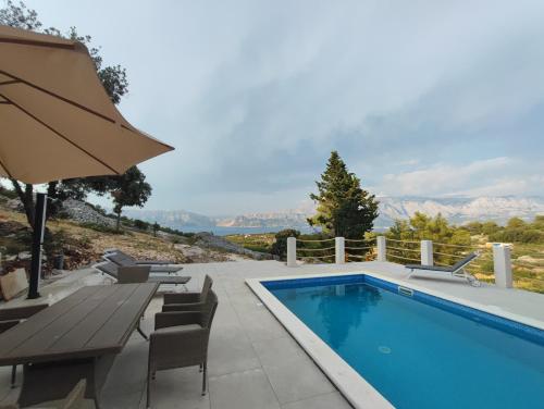 een zwembad met een tafel en stoelen en een parasol bij Villa Bob in Povlja