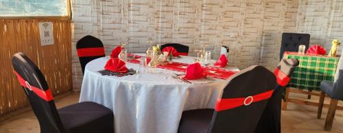 une table avec une nappe blanche et des chaises rouges et noires dans l'établissement Little Amanya Camp, à Amboseli