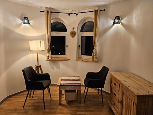 2 Stühle und ein Tisch in einem Zimmer mit 2 Fenstern in der Unterkunft Willa Szewcula Apartament Klimczok in Szczyrk
