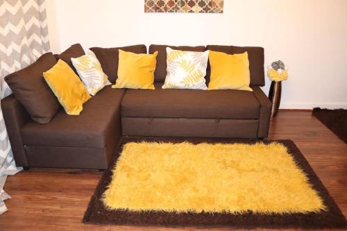 a brown couch with yellow pillows and a yellow rug at Dove's Place in historic Rochester with Parking in Strood