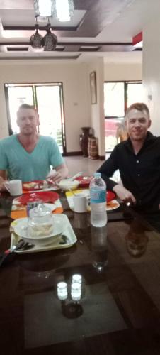two men sitting at a table with plates of food at Villa Cresenciana in Batuan