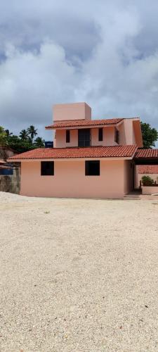 una gran casa rosa con techo rojo en Beira mar maragogi, en Maragogi