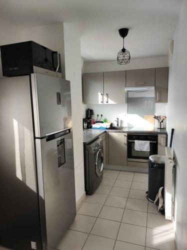 une cuisine avec un réfrigérateur et un lave-vaisselle dans l'établissement Charmant appartement proche Paris, à Eaubonne