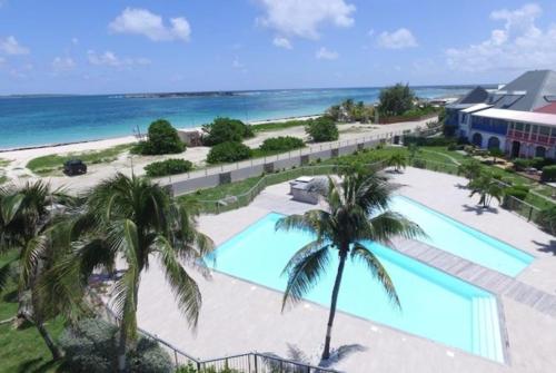 Una vista aérea de un resort con piscina y el océano. en Sur la plage de la Baie Orientale - Bel appartement VUE MER 6à7p, en Orient Bay