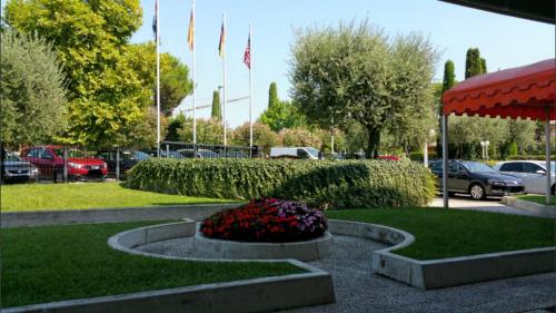 a park with flags and flowers in a park at Hotel Holiday in Sirmione