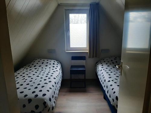 two twin beds in a small room with a window at Stijlvol aan de visvijver in Gramsbergen