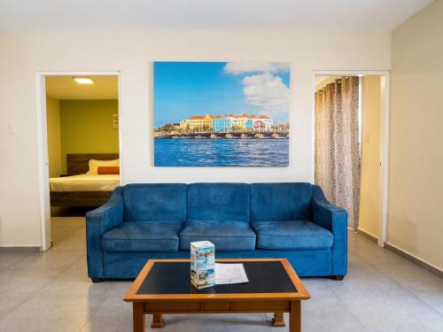 a living room with a blue couch and a table at DeLynne Resort Curaçao in Willemstad