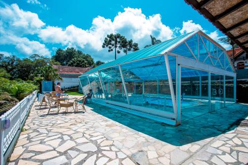 a glass greenhouse on a patio with a table and chairs at Pousada das Videiras in Monte Verde