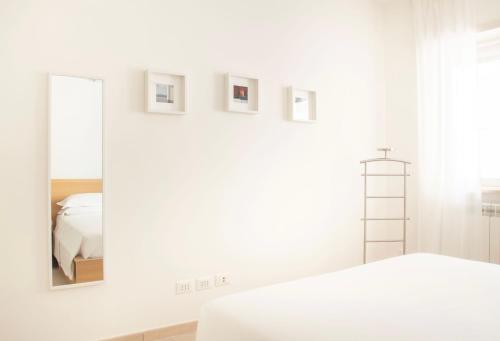 biała sypialnia z lustrem i łóżkiem w obiekcie Appartamento Moderno e Luminoso (Metro B) w Rzymie