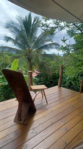 una terrazza in legno con sedia e ombrellone di Tipi bana a Capesterre-Belle-Eau