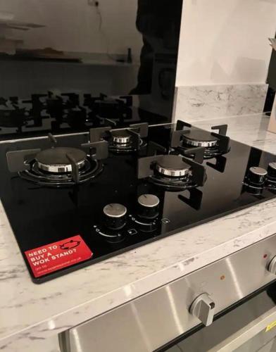 a stove top with four burners on a kitchen counter at The Luxury Inn 02 in Birmingham