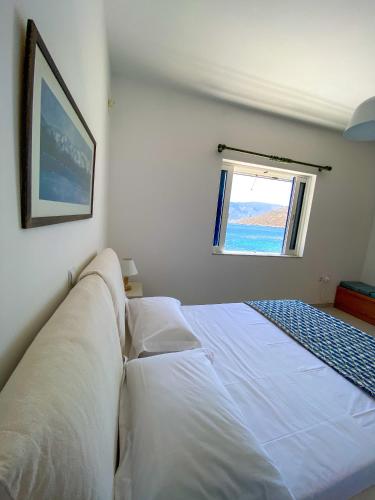 a white bed in a bedroom with a window at Aegean Aura Apartment III in Kalymnos